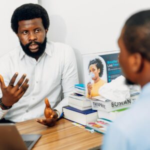 A man sitting at a desk talking to another man