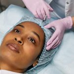 Close-up of a cosmetic procedure using injectables on a woman's forehead in a clinic setting.